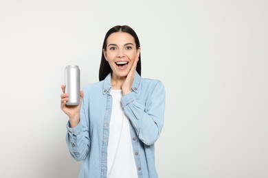 Photo of Beautiful happy woman holding beverage can on light grey background. Space for text