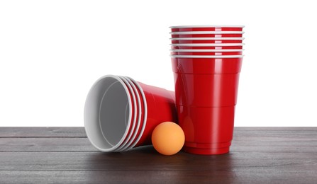 Plastic cups and ball for beer pong on wooden table against white background