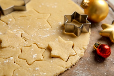 Photo of Raw Christmas cookies, cutters and festive decor on table