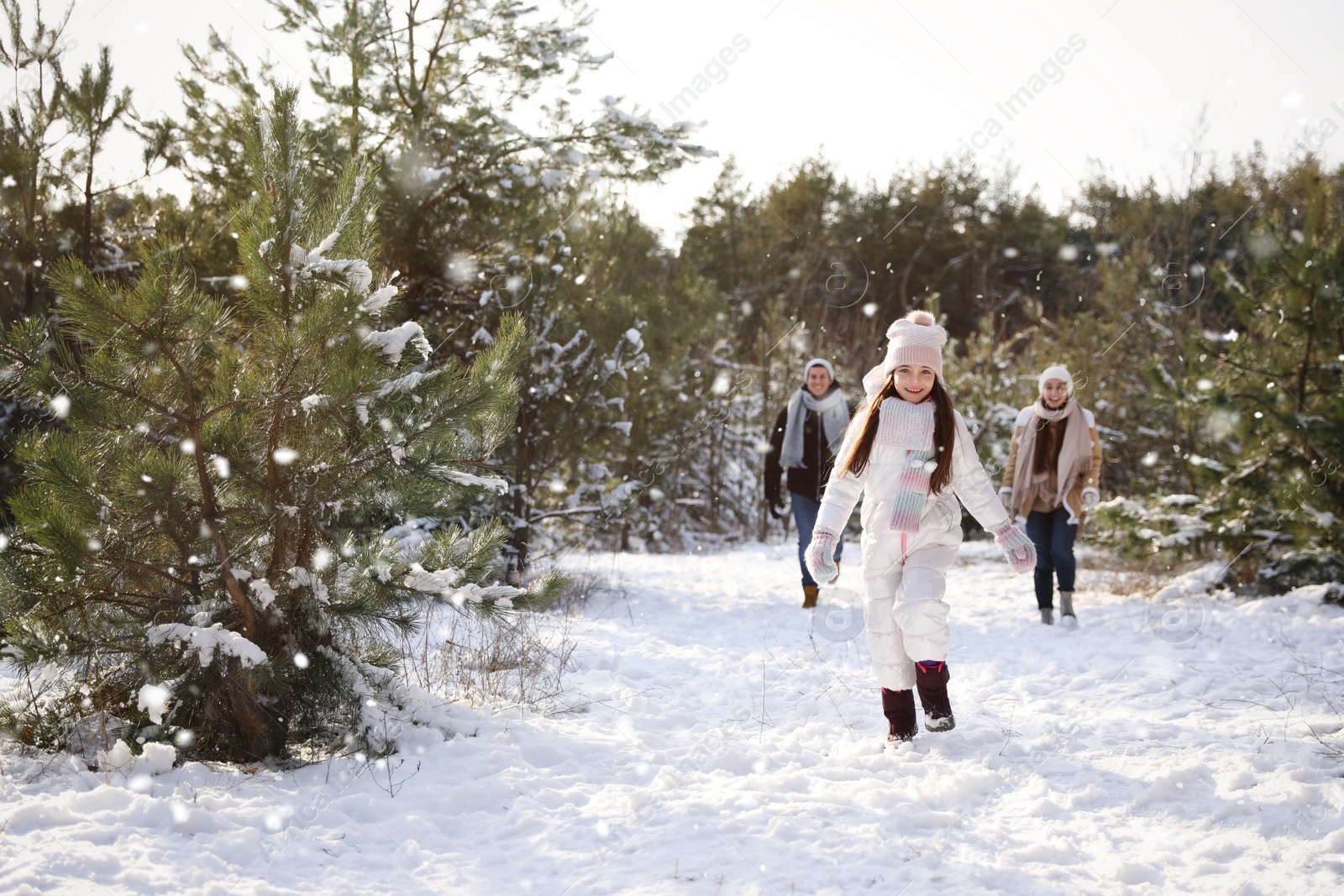 Photo of Cute little girl with her parents outdoors on winter day. Christmas vacation