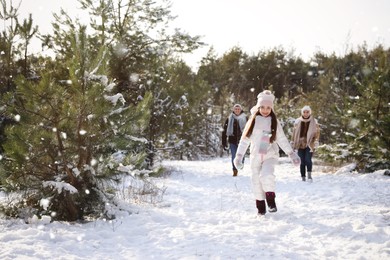 Photo of Cute little girl with her parents outdoors on winter day. Christmas vacation