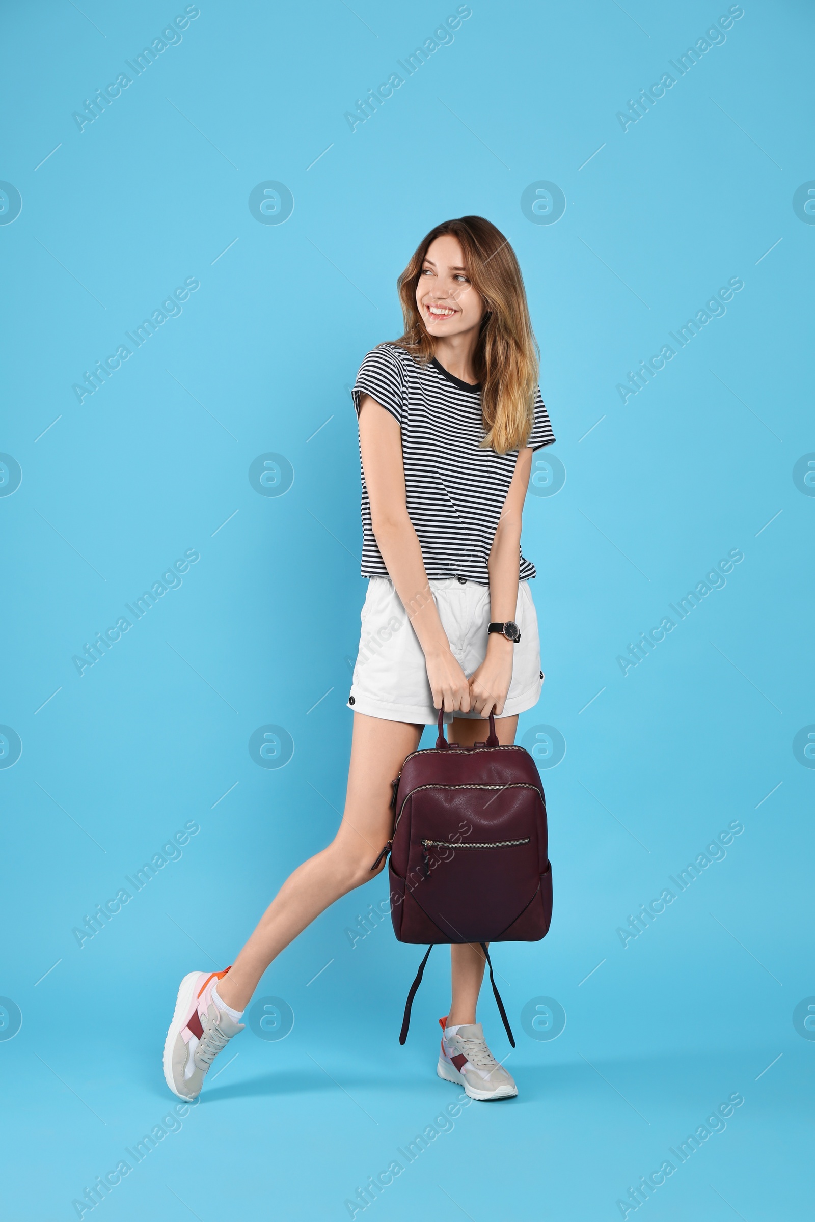 Photo of Happy woman with backpack on light blue background