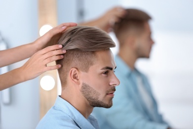 Photo of Professional hairdresser working with young man in barbershop. Trendy hair color