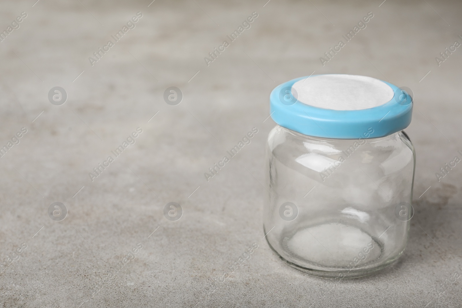 Photo of Empty glass jar on grey table, space for text