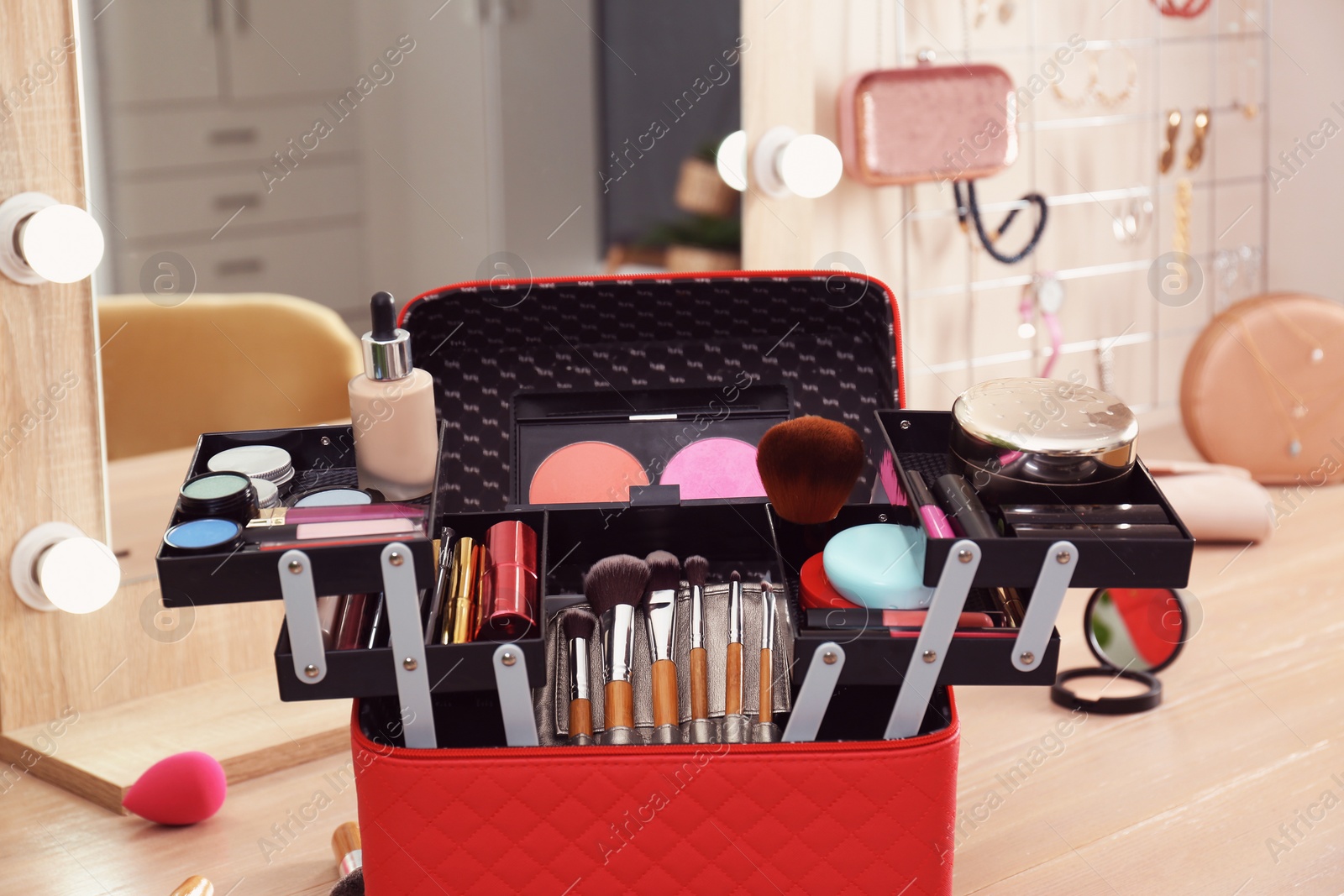 Photo of Beautician case with professional makeup products and tools on wooden dressing table