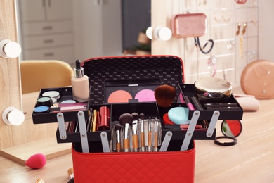 Photo of Beautician case with professional makeup products and tools on wooden dressing table