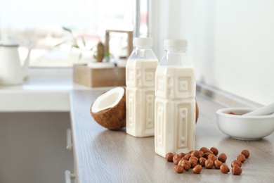 Photo of Bottles with milk substitute and nuts on kitchen table