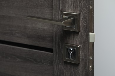 Photo of Open wooden door with metal handle, closeup