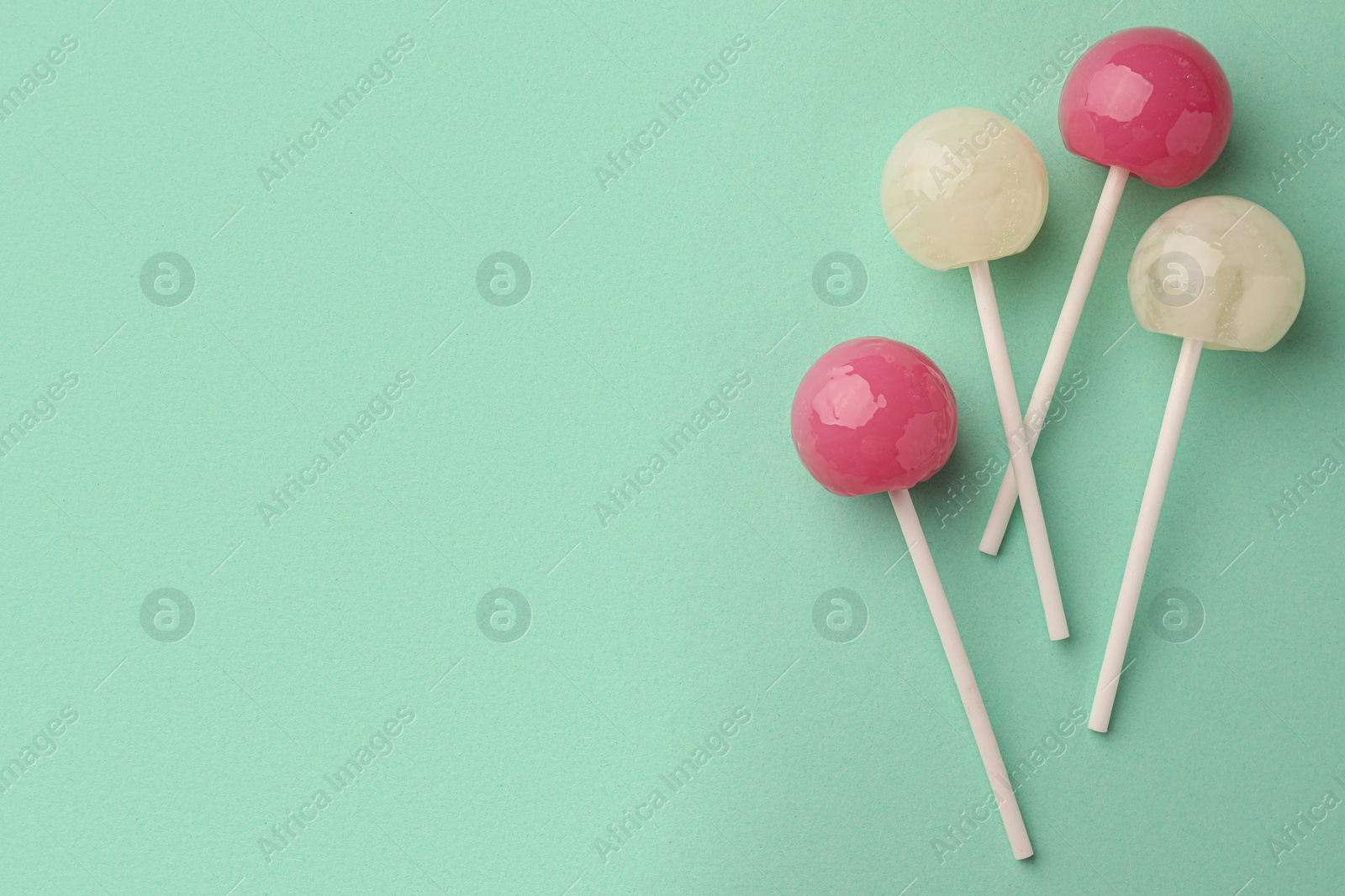 Photo of Tasty lollipops on turquoise background, flat lay. Space for text