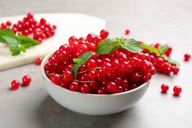 Photo of Delicious red currants and mint in bowl on light grey table