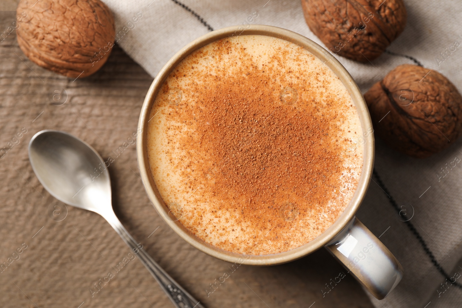 Photo of Delicious eggnog with cinnamon and walnuts on wooden table, flat lay. Space for text