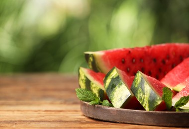 Photo of Slices of delicious ripe watermelon on wooden table outdoors, closeup. Space for text