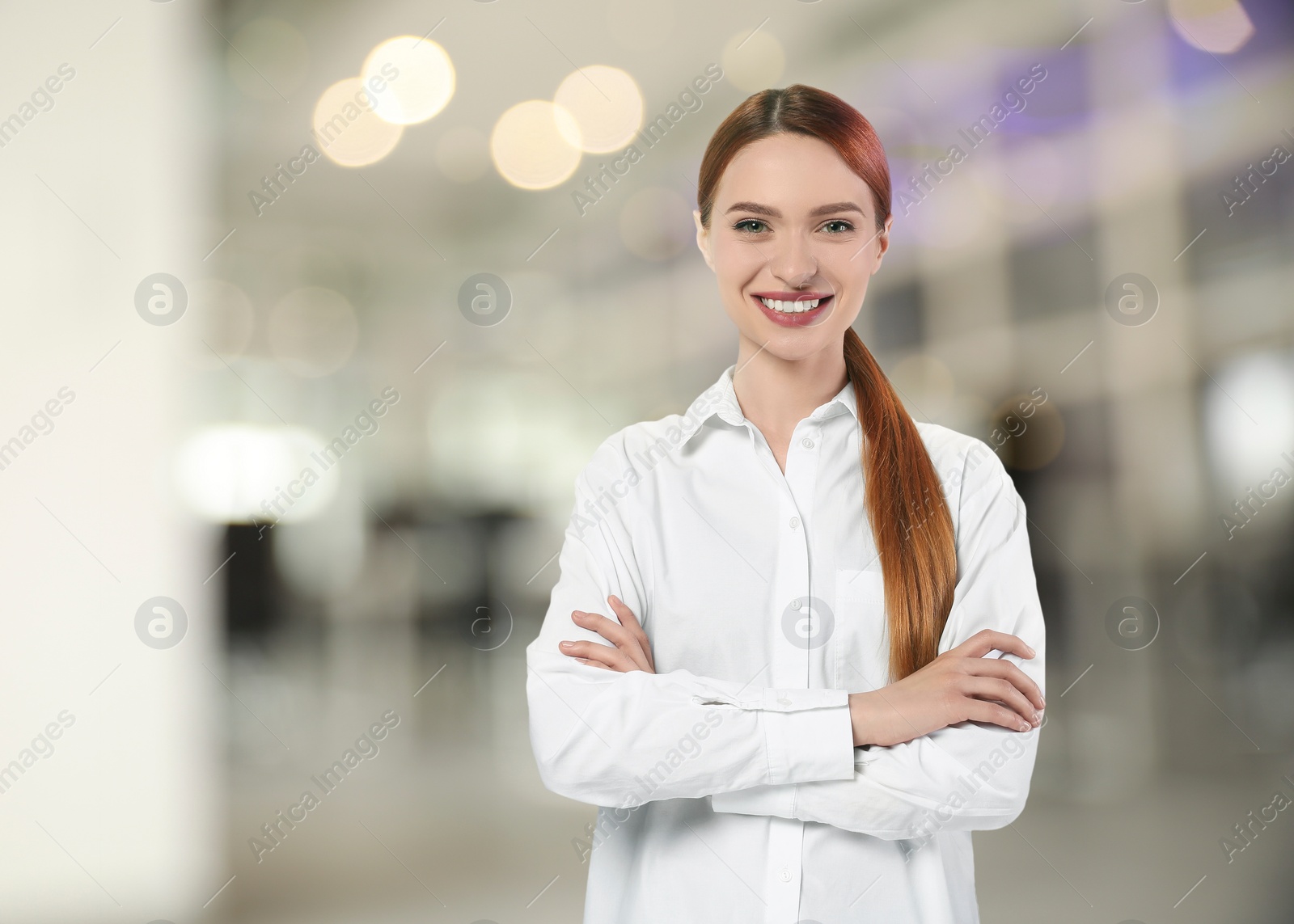 Image of Portrait of happy woman in office. Pretty girl looking at camera and smiling on blurred background