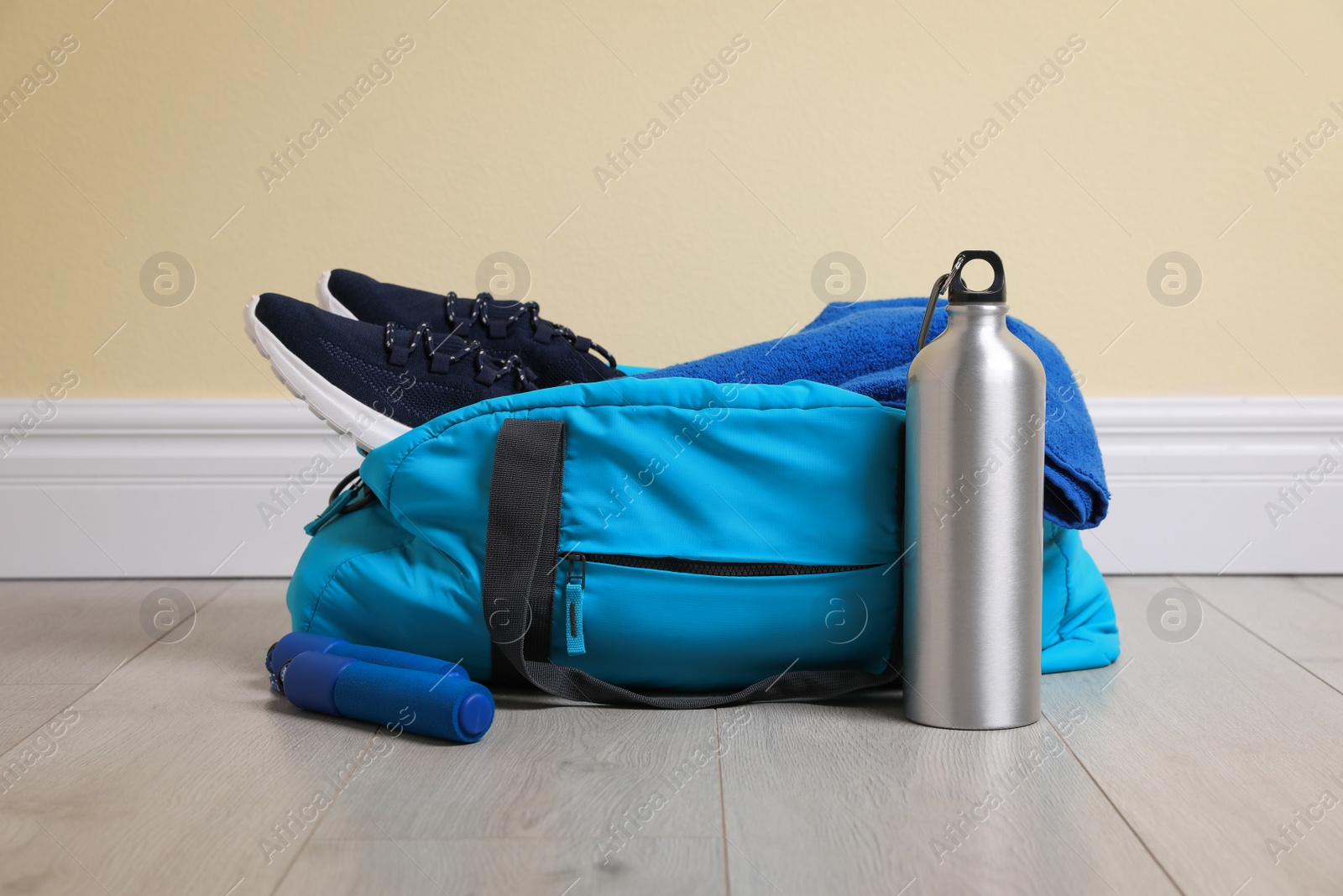 Photo of Bag with different sports equipment on wooden floor indoors