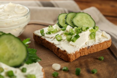 Photo of Delicious sandwiches with cream cheese, cucumber and chives on wooden board, closeup