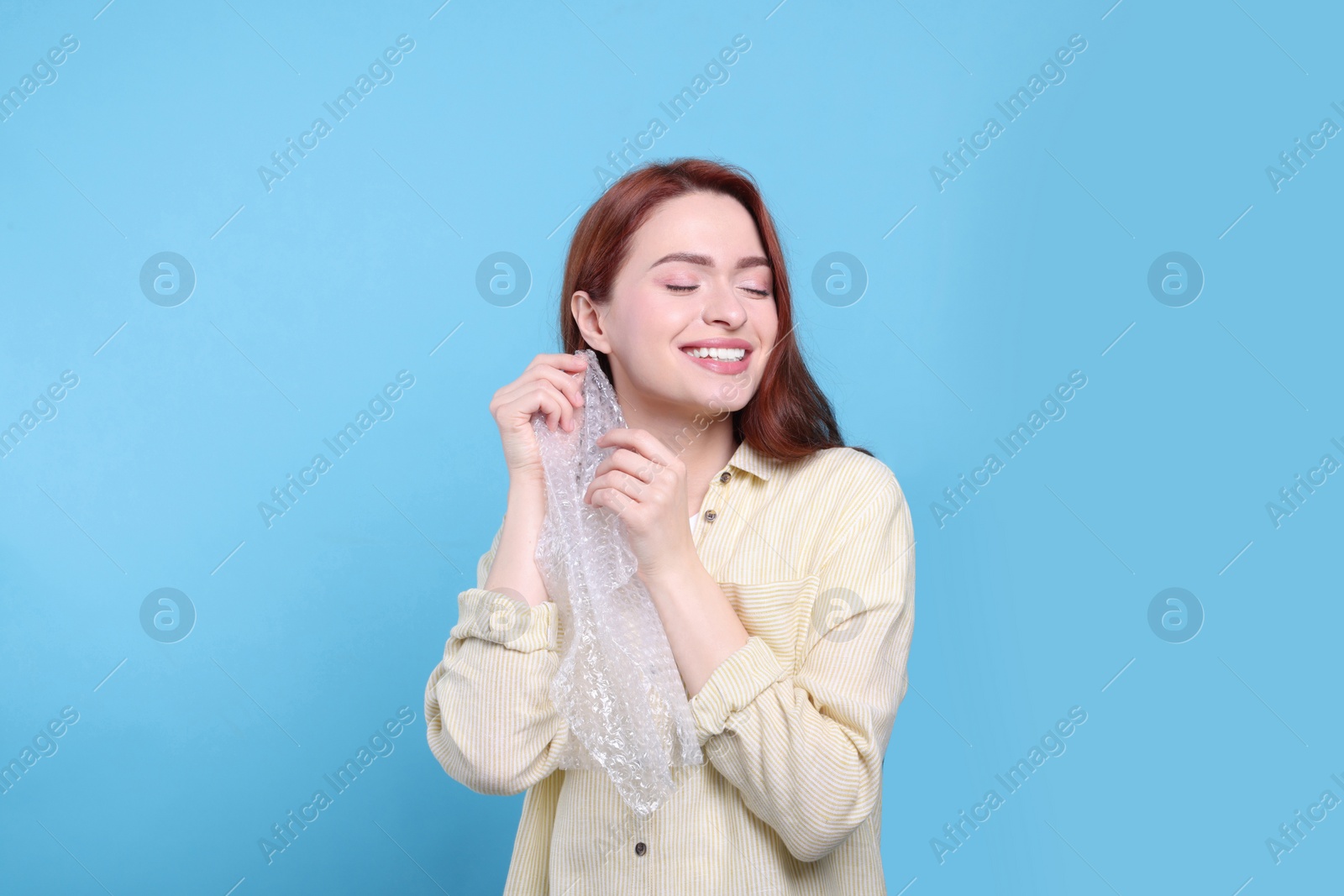 Photo of Woman popping bubble wrap on turquoise background. Stress relief