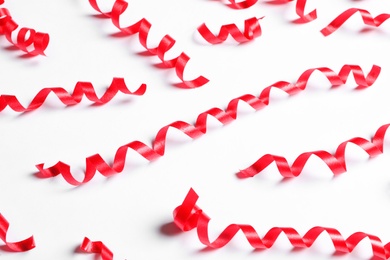 Photo of Many red serpentine streamers on white background