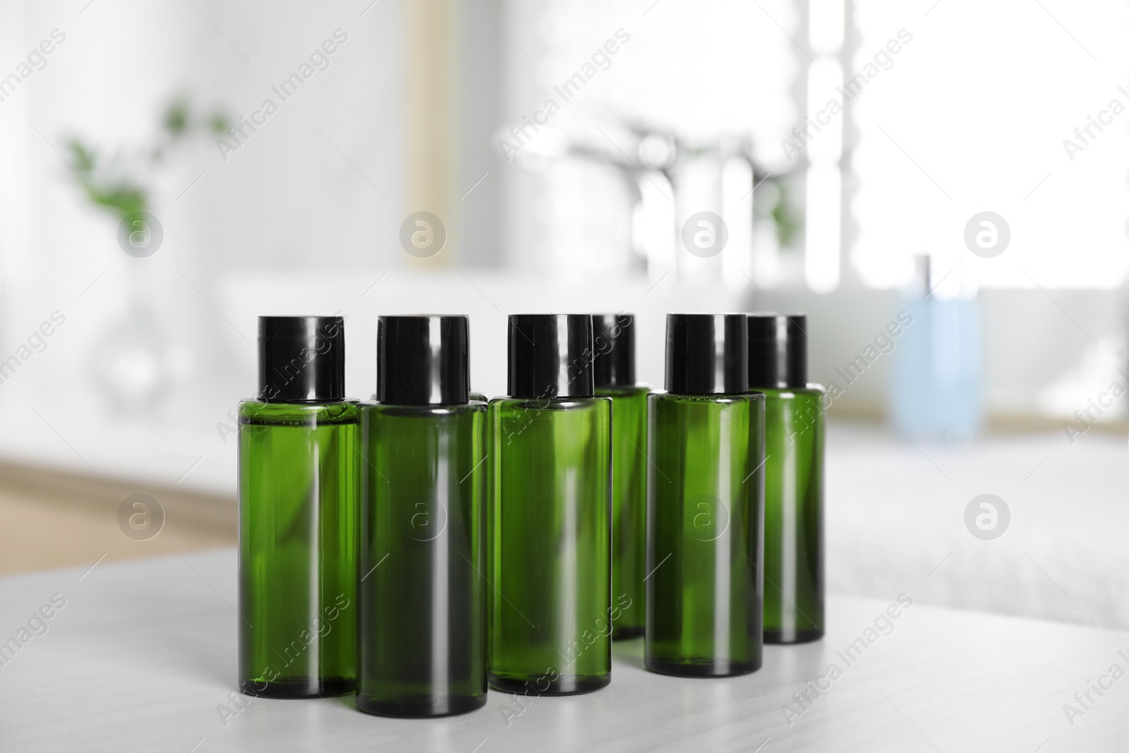 Photo of Mini bottles with cosmetic products on white table in bathroom