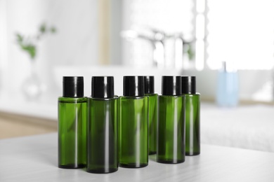 Mini bottles with cosmetic products on white table in bathroom