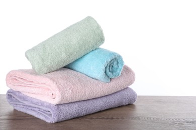 Photo of Fresh towels on wooden table against white background