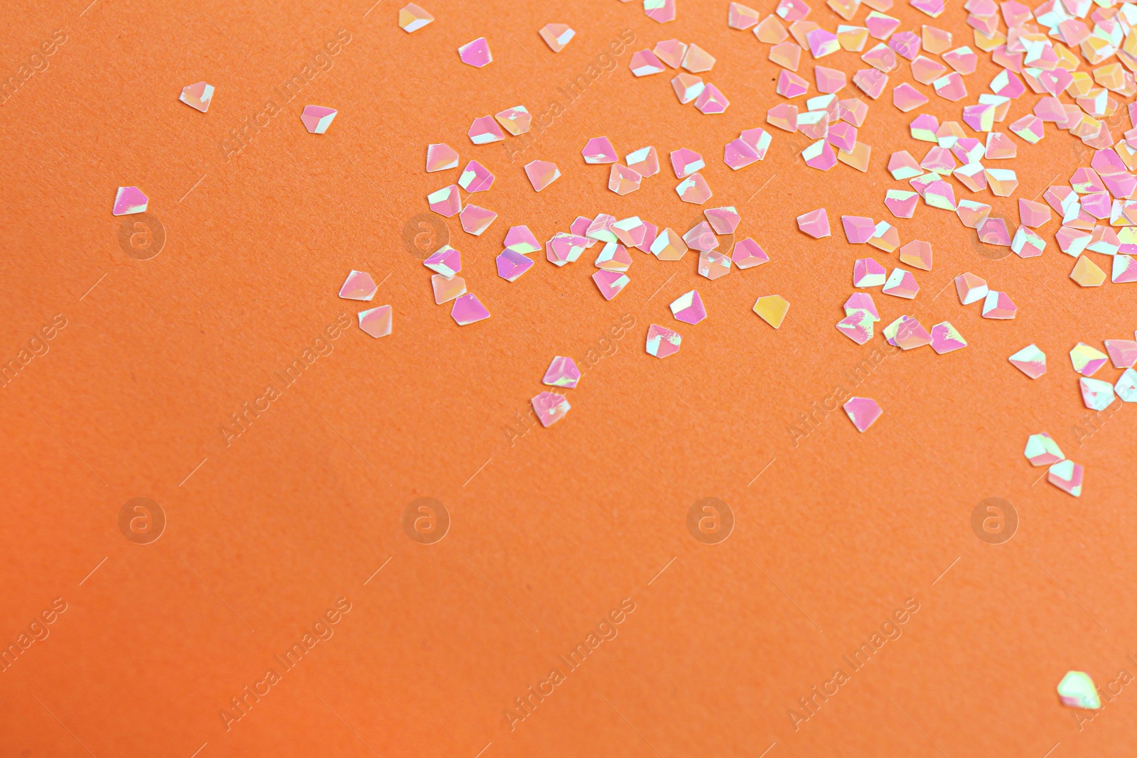 Photo of Shiny bright pink glitter on coral background. Space for text