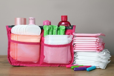 Photo of Different menstrual pads, tampons and skin care products on wooden table