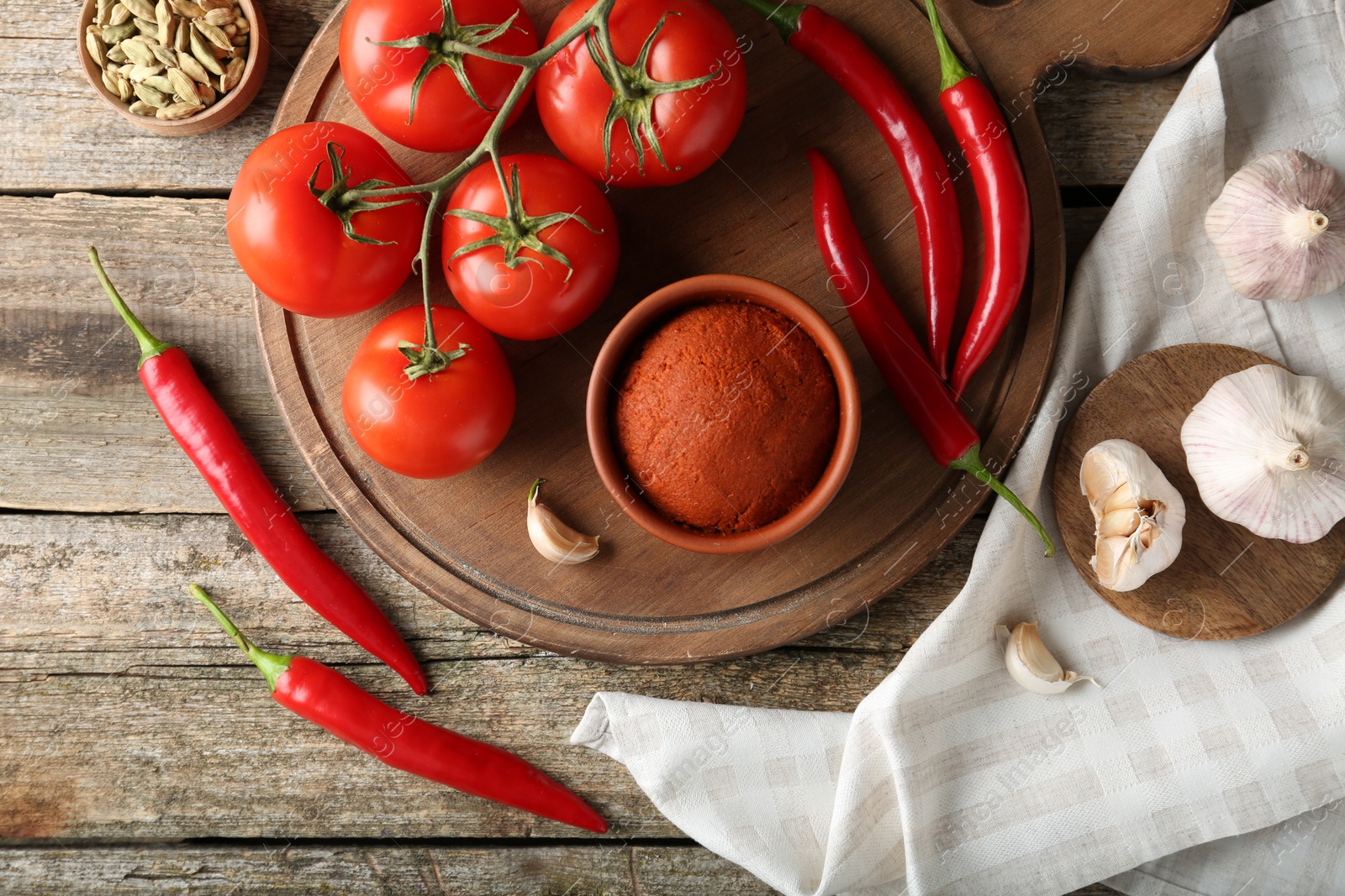 Photo of Red curry paste in bowl and ingredients on wooden table, flat lay