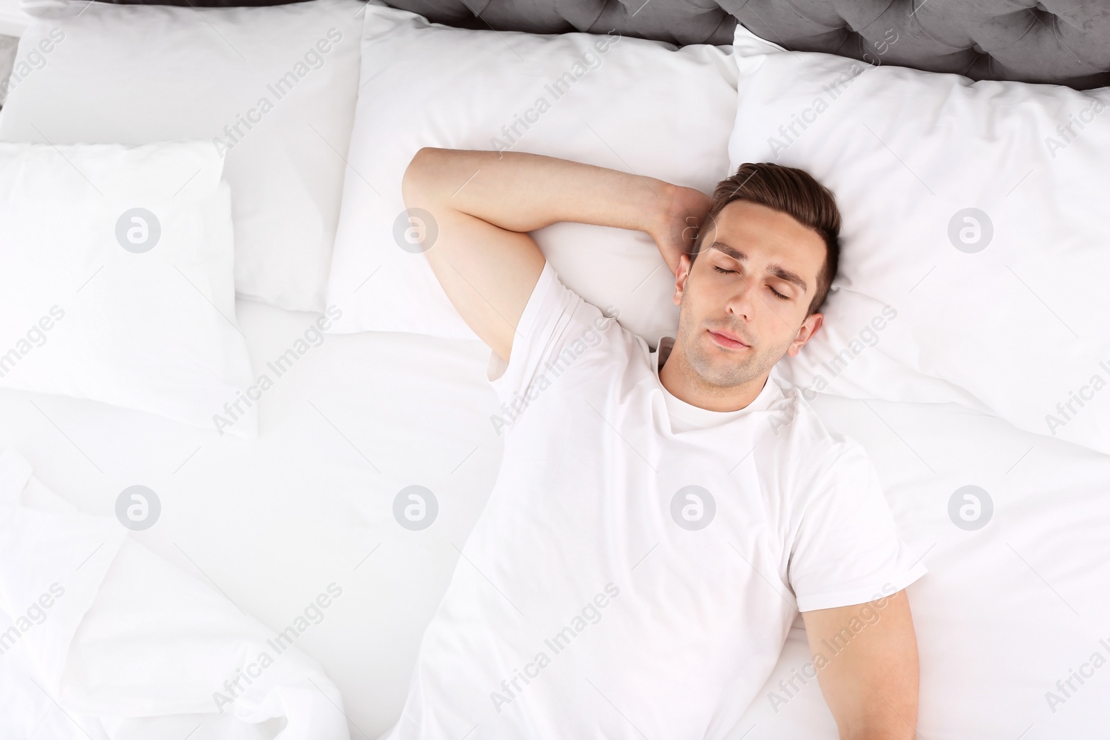 Photo of Young man sleeping in bed at home, top view