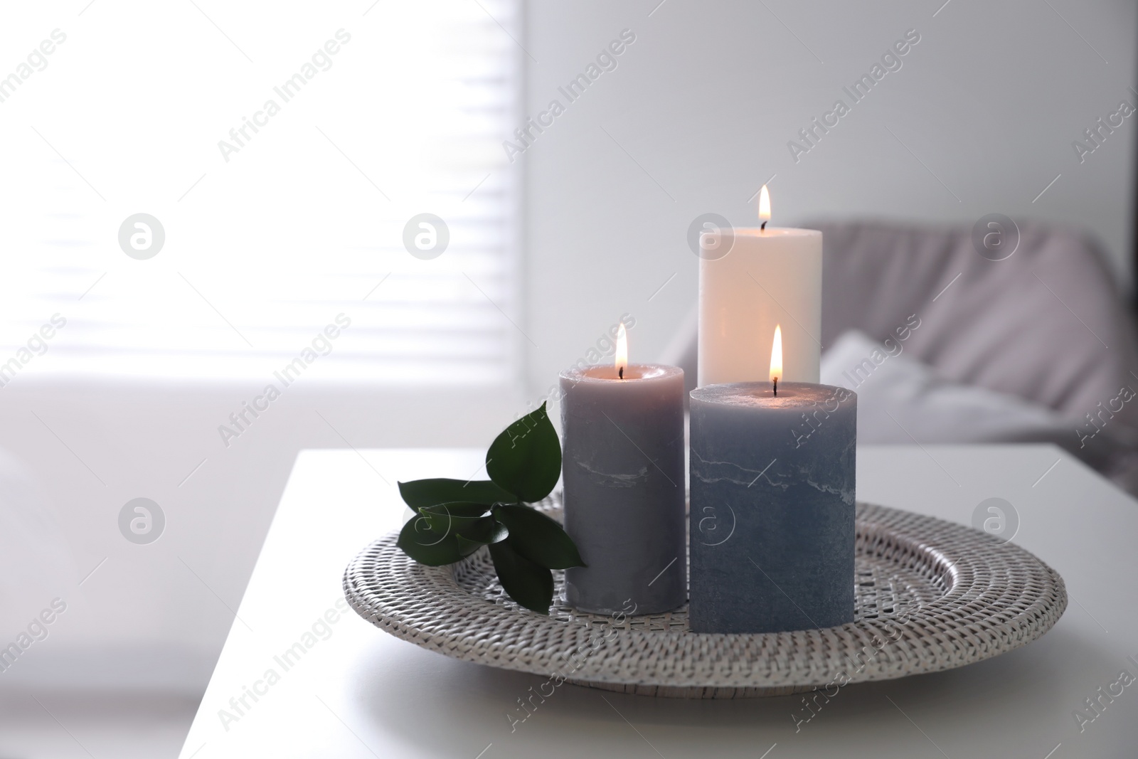 Photo of Tray with burning candles and leaves on white table indoors. Space for text