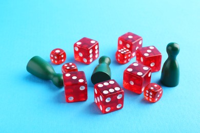 Photo of Many red dices and color game pieces on light blue background