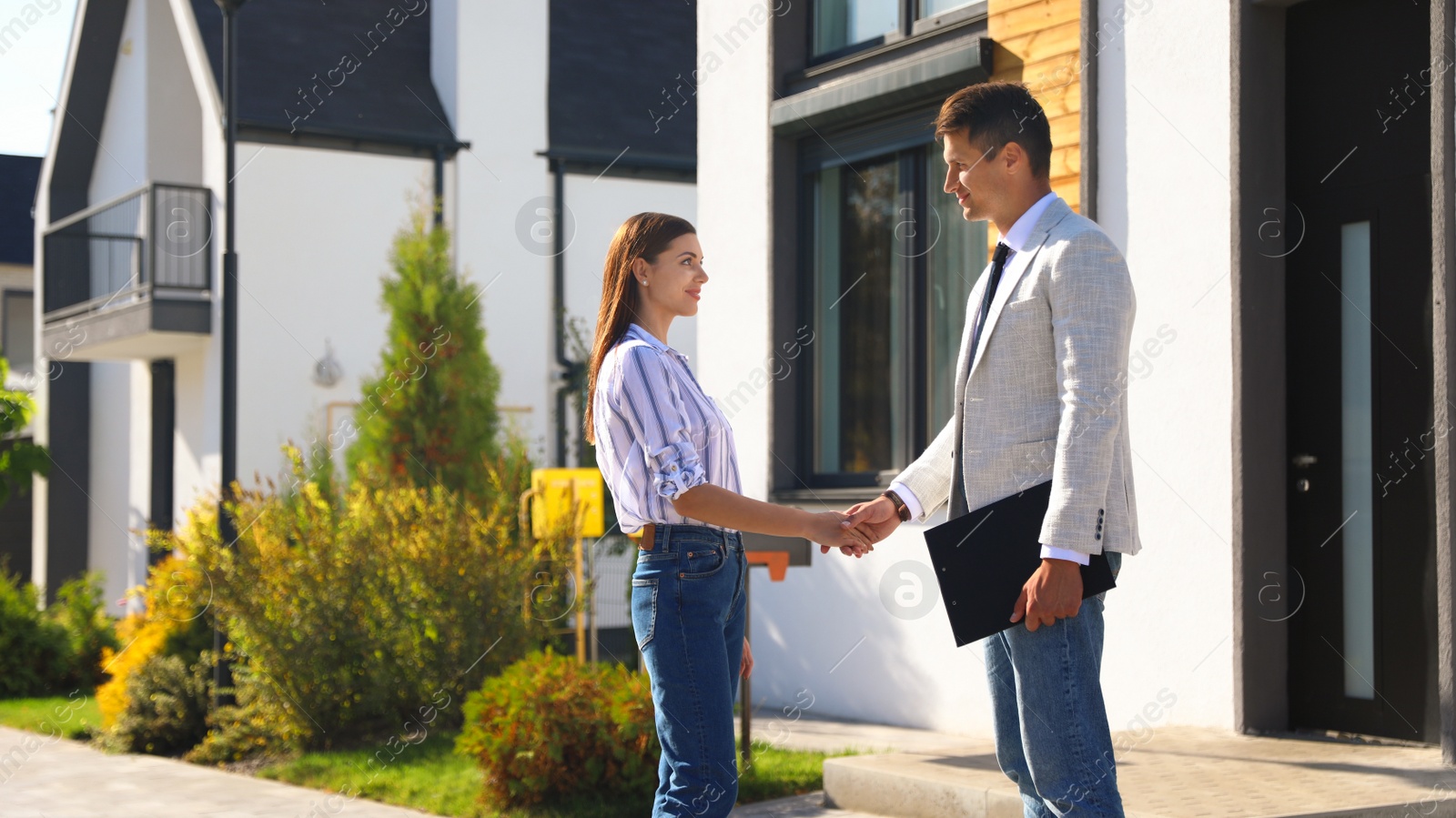 Photo of Real estate agent shaking hands with young woman outdoors