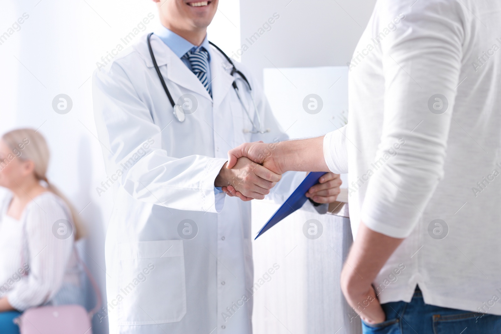 Photo of Doctor and patient shaking hands in hospital hall, closeup