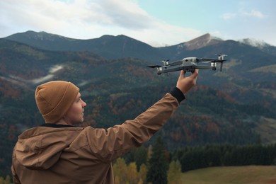 Young man with modern drone in mountains