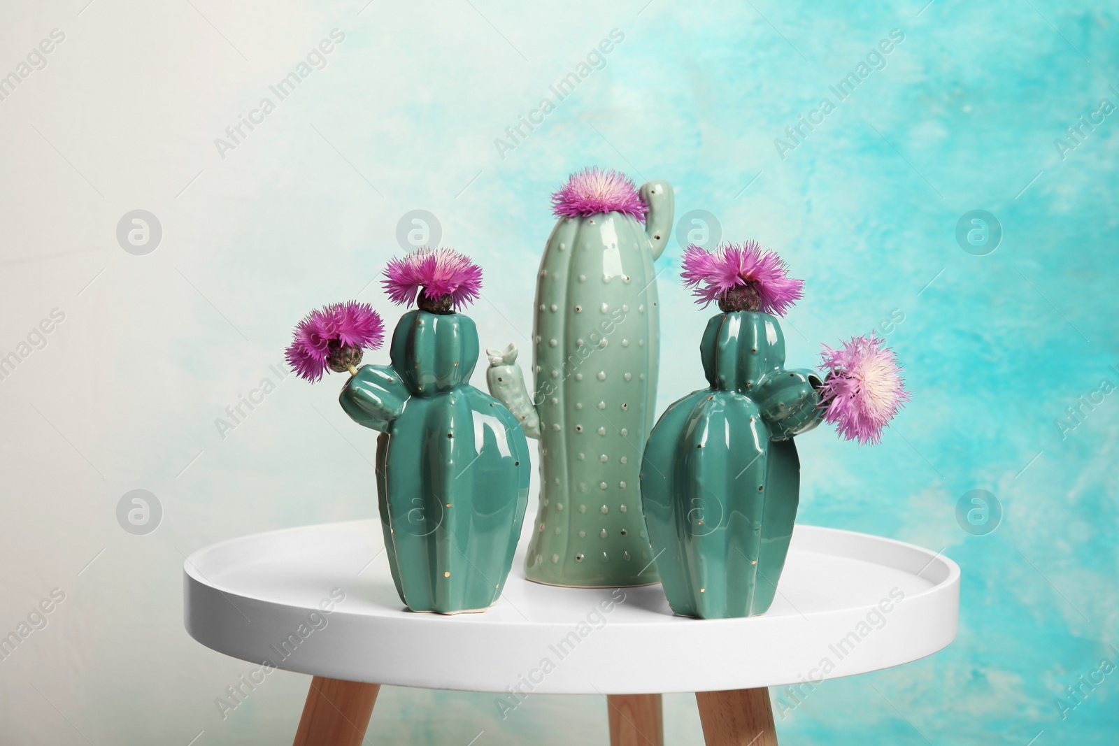 Photo of Trendy cactus shaped ceramic vases with flowers on table