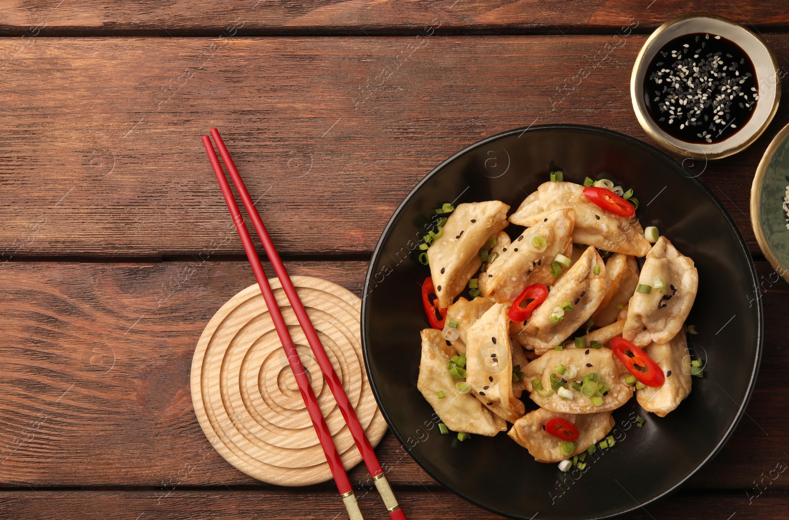 Photo of Delicious gyoza (asian dumplings) served on wooden table, flat lay