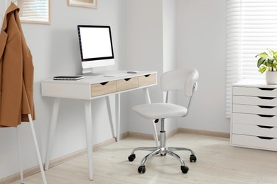 Stylish office interior with comfortable chair, desk and computer