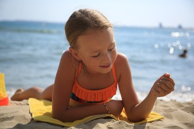 Little girl playing with sand on beach near sea