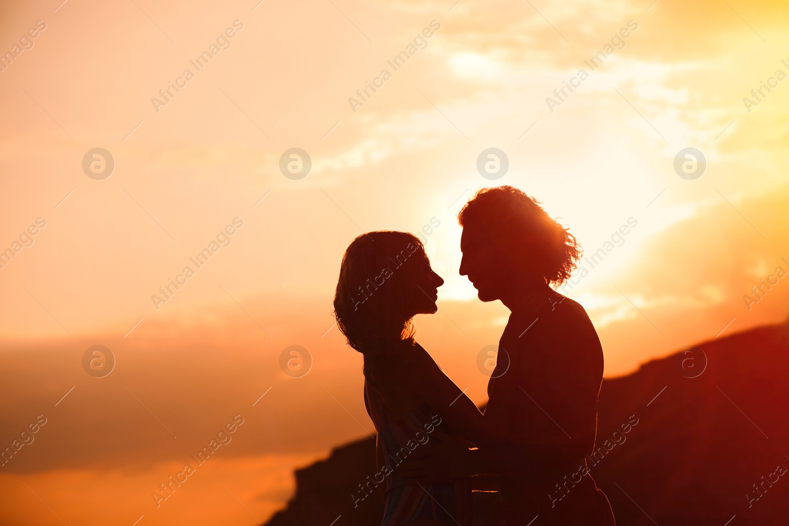 Photo of Young woman in bikini and her boyfriend on beach at sunset. Lovely couple