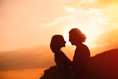 Photo of Young woman in bikini and her boyfriend on beach at sunset. Lovely couple