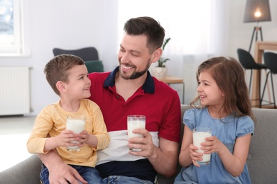 Photo of Happy family with glasses of milk in living room