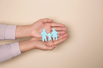 Young woman holding paper family cutout on color background