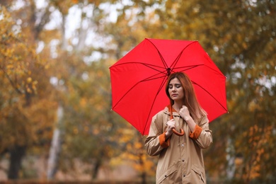 Woman with umbrella in autumn park on rainy day