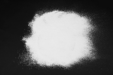 Photo of Pile of flour on black table, top view
