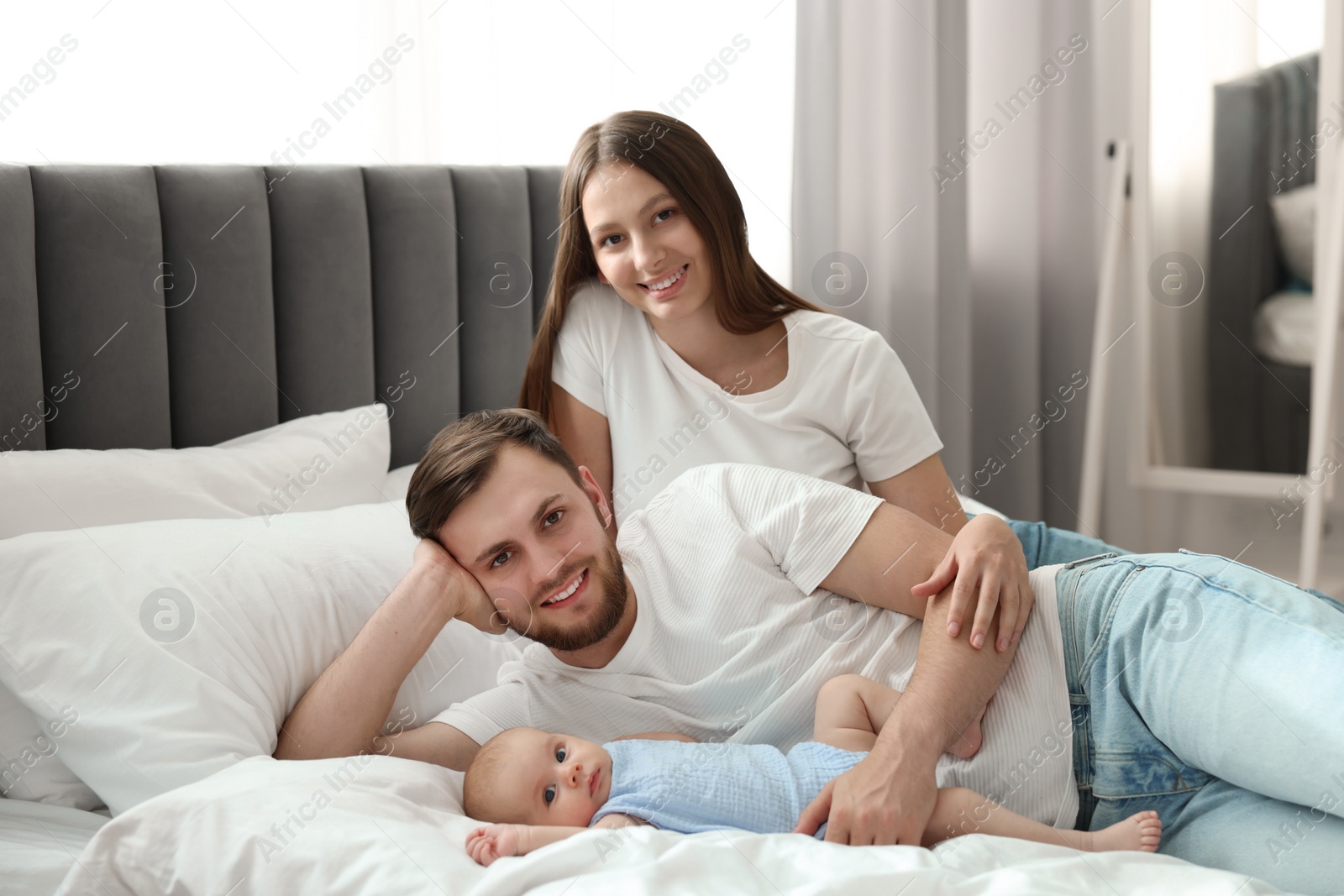 Photo of Happy family. Parents with their cute baby on bed indoors