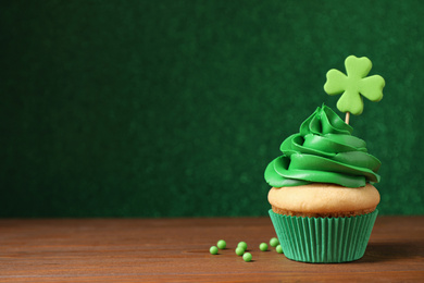 Photo of Delicious decorated cupcake on wooden table, space for text. St. Patrick's Day celebration