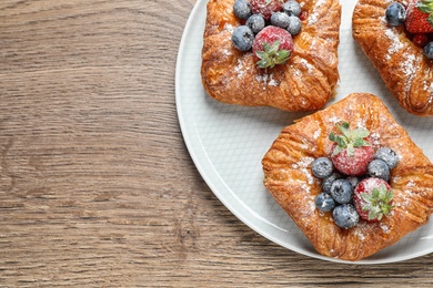 Fresh delicious puff pastry with sweet berries on wooden table, top view. Space for text