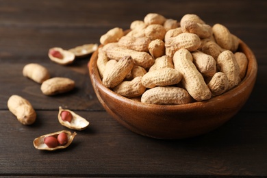 Bowl with peanuts in shell on table