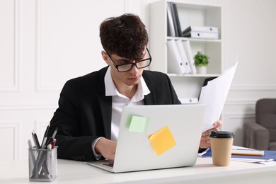 Photo of Young man working at white table in office. Deadline concept