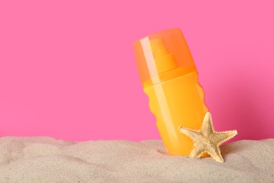 Photo of Suntan product and starfish on sand against pink background. Space for text