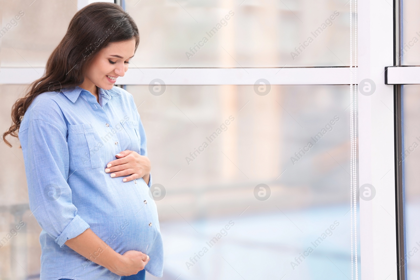 Photo of Beautiful pregnant woman near window at home